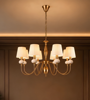 Detailed view of ivory pleated chandelier shades, decorative ribbed accents, and polished gold-tone metal fittings.
Copy alt text