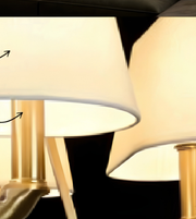 Close-up of a luxury gold chandelier with five ivory tapered shades, curved metal arms, and decorative central detailing.
Copy alt text