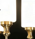 Close-up detail of a white cylindrical chandelier shade with a gold-tone metal fitting against a dark background.