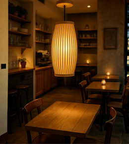 Modern barrel pendant light glowing above dining table in café