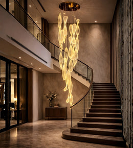 Elongated acrylic flame cascade chandelier in a luxury staircase with warm ambient lighting