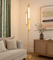 Modern brass floor lamp with vertical light elements beside sofa