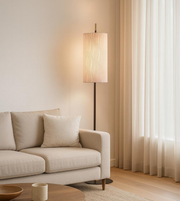 Modern fabric floor lamp with soft ambient glow beside beige sofa