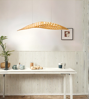 Modern wooden leaf pendant light hanging above a dining table in a minimalist interior