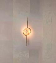 Modern wall sconce with a warm glow on a textured wall.

