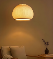 Light fixture casting a warm glow in a room with a vase and books on a table.