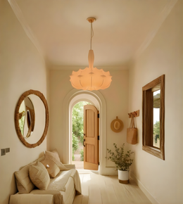 Nestled hallway with a light fixture, round mirror, and wooden door.