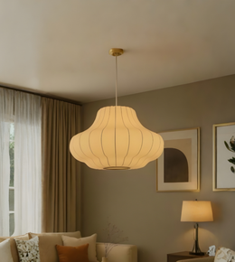Light fixture hanging in a living room with a couch and framed pictures on the wall.