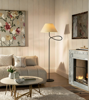 Modern black floor lamp with looped metal design beside sofa