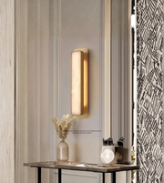 Vertical modern wall sconce with warm ambient glow on paneled wall