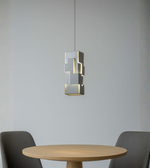 Modern grey geometric column pendant light above dining table with soft ambient lighting