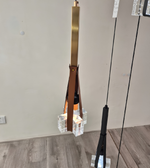 Modern pendant light fixture with a brown leather strap and glass elements on a neutral background.