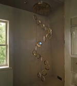 Chandelier with gold circular design hanging in a room with a window and door.