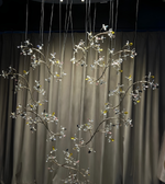 Decorative hanging branches with clear glass elements against a neutral background