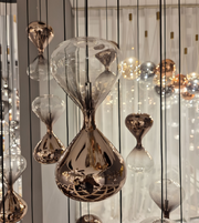 Decorative hourglass-shaped lamps hanging against a neutral background