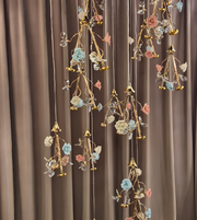 Decorative hanging floral arrangements with gold accents against a brown curtain background