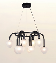 A modern multi-light chandelier with a matte black curved metal frame and multiple frosted white glass globes, suspended from a circular black ceiling canopy against a plain off-white background.