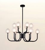 A modern 9-light chandelier with a matte black metal frame and frosted white glass shades, shown illuminated against a warm off-white background.