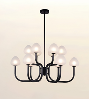 A modern 9-light chandelier with a matte black metal frame and frosted white glass shades, shown illuminated against a warm off-white background.
