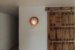 Minimalist wall-mounted light installed in hallway near wooden door