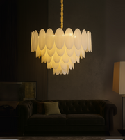 Feather-inspired golden chandelier cascading above a modern dining area