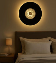 Modern circular wall light above bed in cozy bedroom with neutral decor