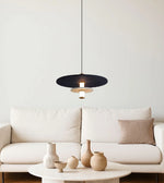 Modern black pendant light above cream sofa and round table with ceramic vases in minimalist living room