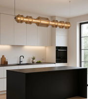 Modern kitchen with sculptural gold pendant light, black island, and minimalist decor