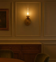 Modern brass wall sconce glowing in elegant dining room with wood cabinet and paneling
