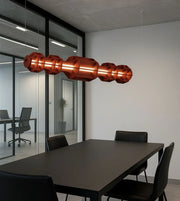 Modern geometric pendant light in office meeting room with black table and chairs